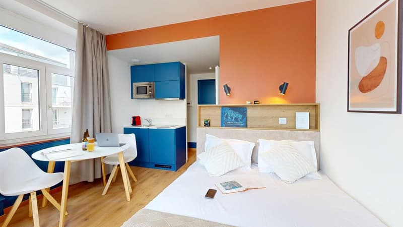 single bed, desk, microwave, sink, window, blue cabinets, lamps, curtain, book, cellphone