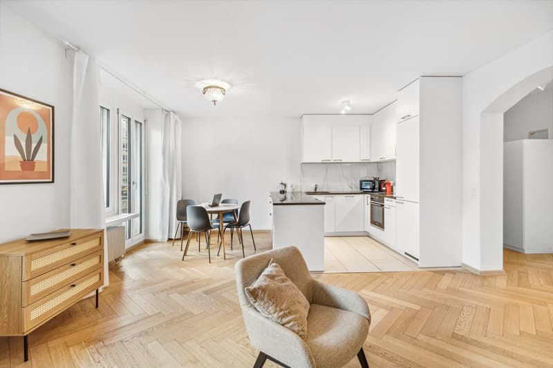 open space with a wooden floor, modern white cabinets, a table, chairs, a desk, a microwave, an oven, a refrigerator, and a picture frame