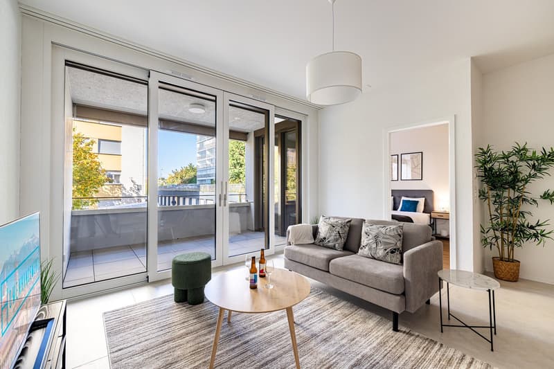 modern living room with sliding glass doors, balcony, gray sofa, wooden coffee table, green ottoman, TV, side table, potted plant