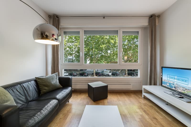 black leather sofa, white coffee table, white TV stand, large window with view of outside