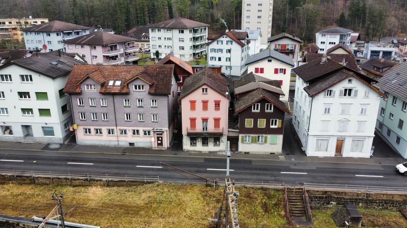 Multiple residential buildings, brown roofs, mix of colors, street, parked cars