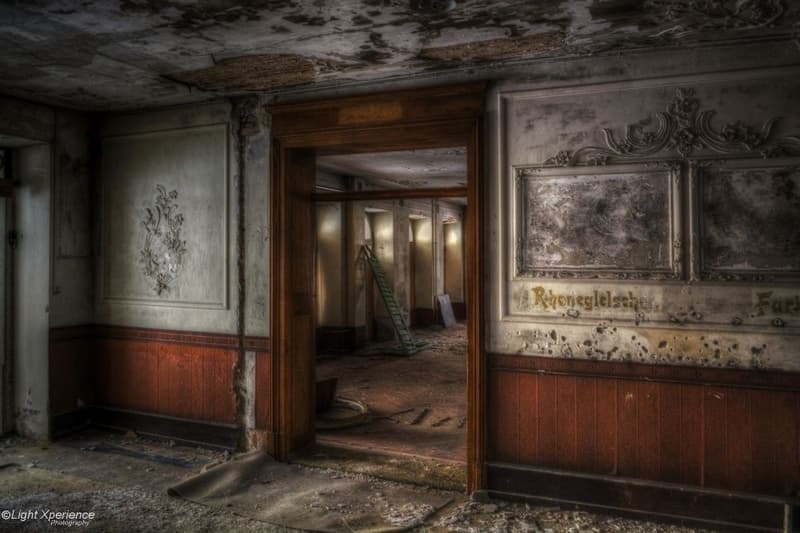 Old room, wooden doors, damaged walls, visible beam, old furniture