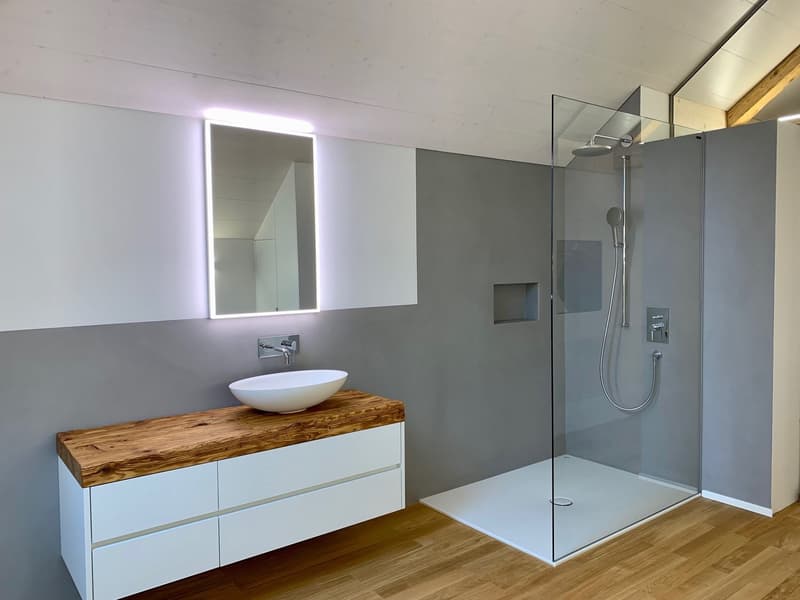 contemporary bathroom with white basin, wooden countertop, glass shower, and mirror with LED light