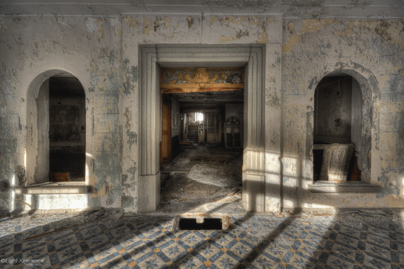 Abandoned building with tiled floors, damaged walls, and visible stairs
