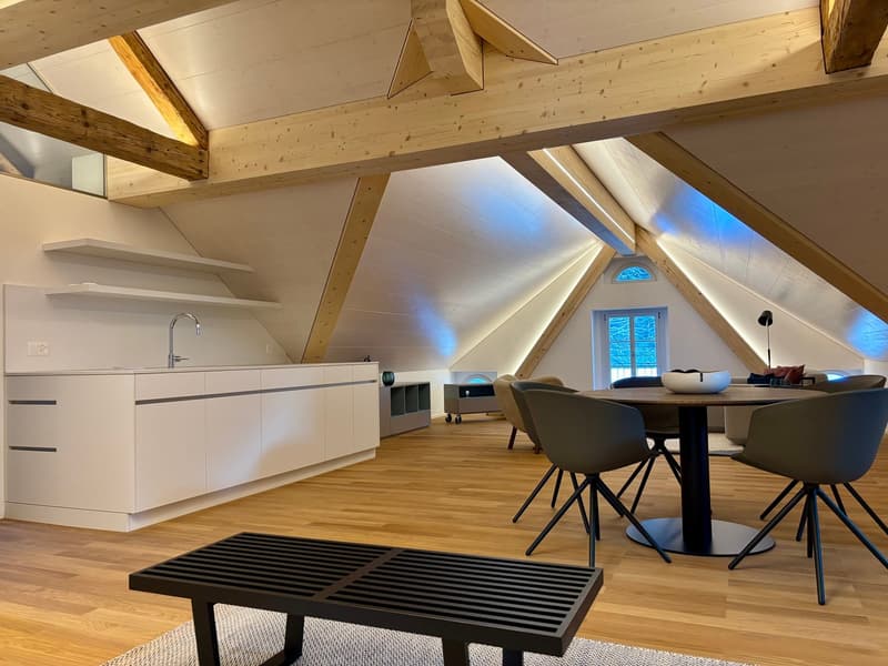 a kitchen with wooden beams, white cabinets, dining table with chairs, and a white couch