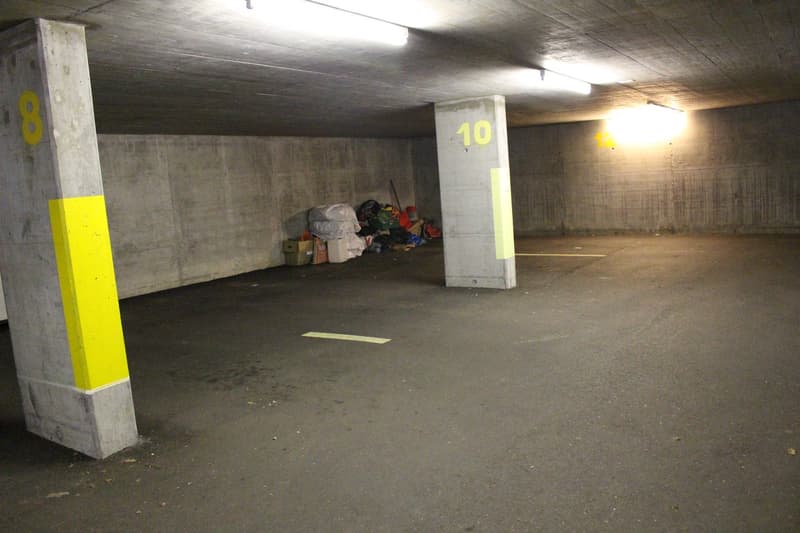 underground parking area with yellow lines on the floor, numbers on the pillars, and fluorescent lights
