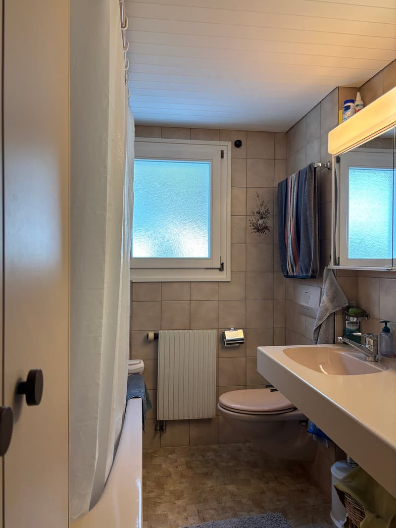 Bathroom with bathtub, toilet, sink, mirror, towel rack, radiator, window