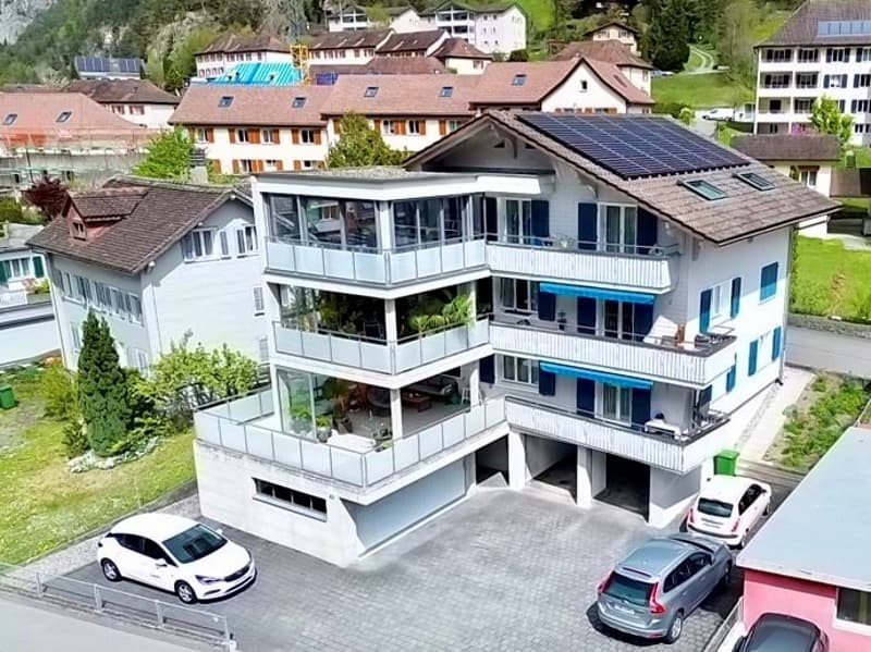 3 story house, white exterior, solar panels on the roof, balconies, garage, cars parked in front