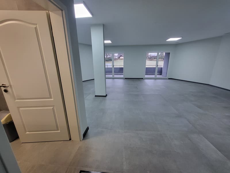 Empty room, gray tiled floor, white walls, glass sliding doors, balcony outside