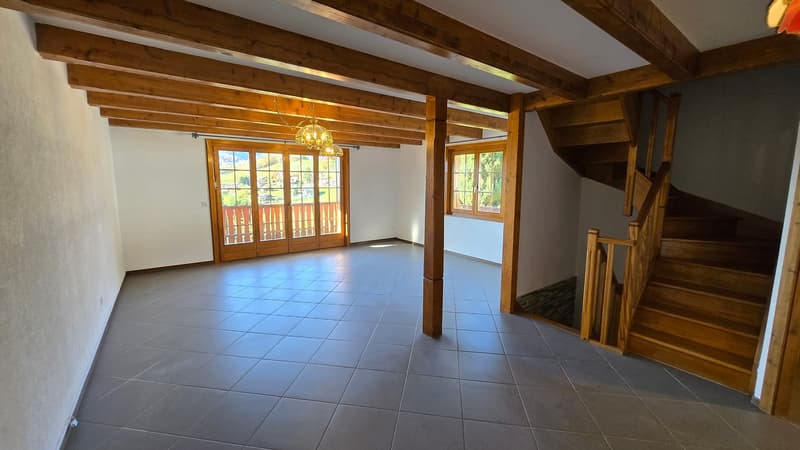 empty room, wooden ceiling beams, tile flooring, large windows, balcony, wooden stairs