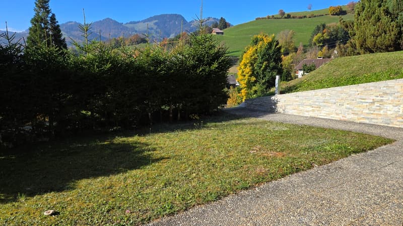 A small grassy lawn, brick wall, gravel driveway