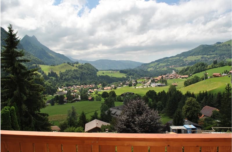 View of a town on green hills with houses and mountains in the background.