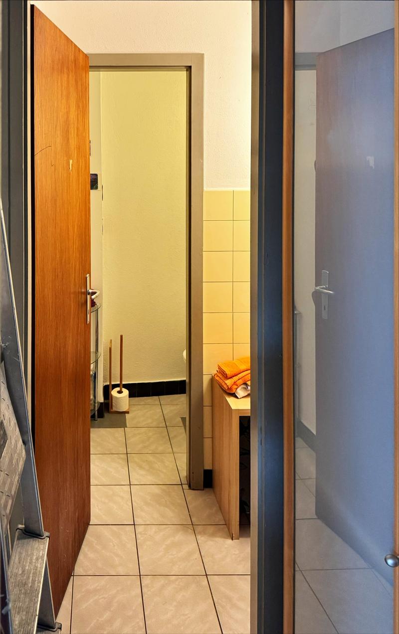 tiled floor, wooden door, small wooden cabinet, toilet paper, towels