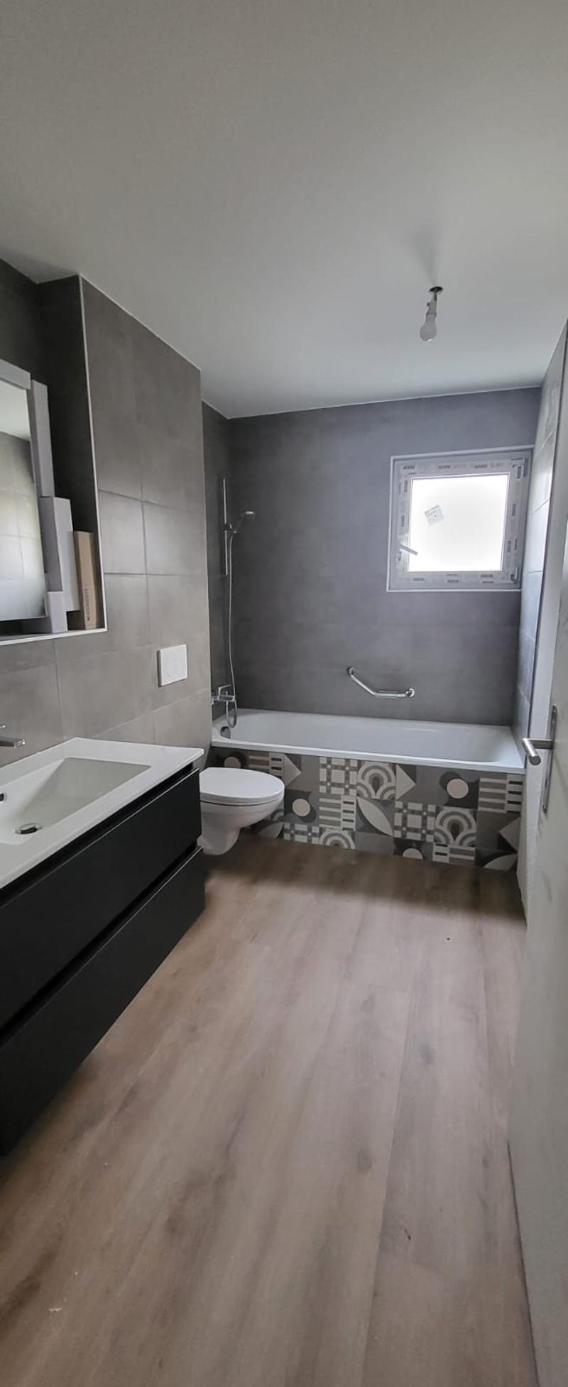 modern bathroom, gray tiles, white bathtub, white sink, black cabinet, white toilet, mirror, window