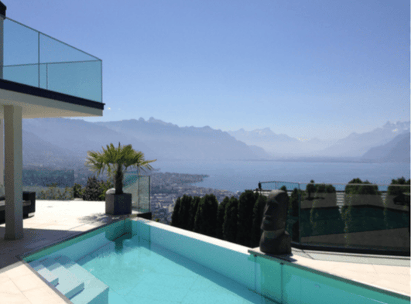 Outdoor area with swimming pool, glass railing, and a view of the mountains and the sea