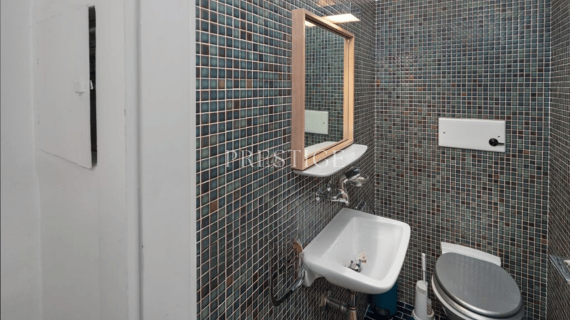 mosaic tiled walls, white sink, mirror, toilet, white toilet roll holder