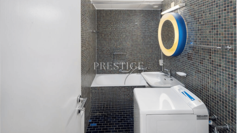 modern tiled bathroom with bathtub, sink, washing machine, circular mirror, shower curtain
