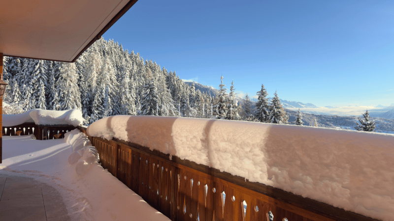 Wooden balcony with railing, balcony covered in snow, view of snowy mountains