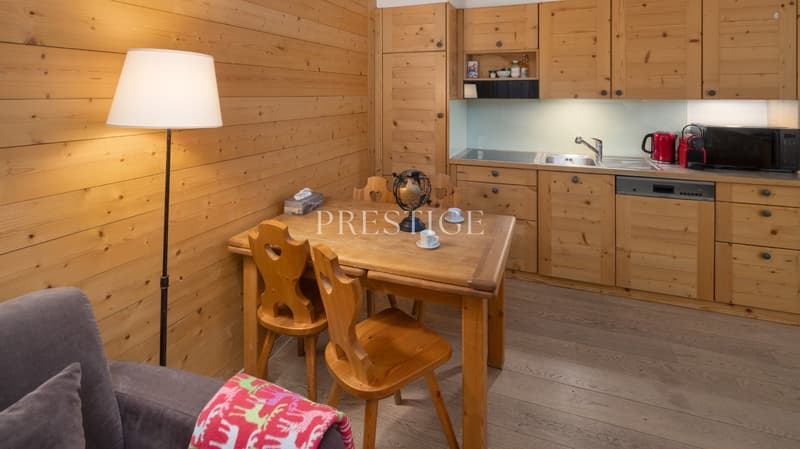 kitchen with dining area, wooden walls, wooden table, wooden chairs, lamp, sink, dishwasher, microwave, kettle