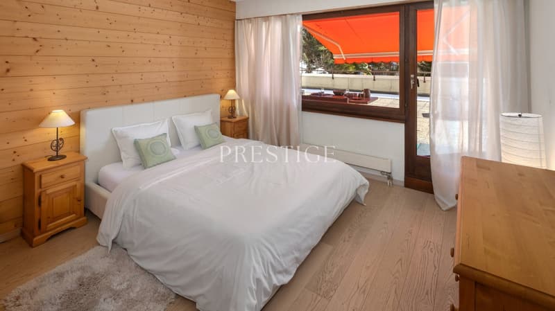 wooden bed, white bedding, wooden nightstands, lamps, wooden wall, large window, balcony, view