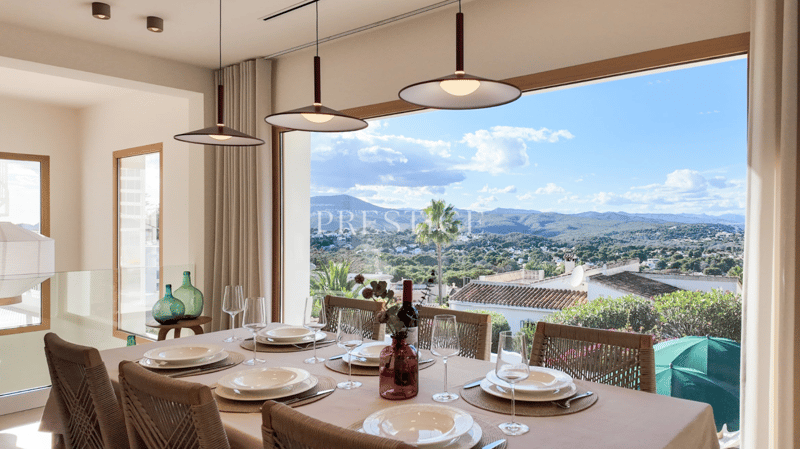 Dining table with chairs, large windows, view of mountains, wine glasses, wine bottle, plates, wine glasses, wine bottle, umbrellas