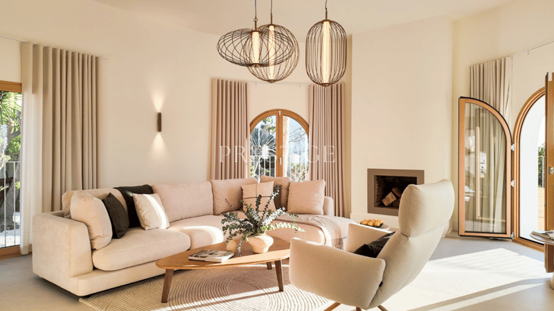 L-shaped sofa, coffee table, armchair, fireplace, large windows, balcony, rug, plant