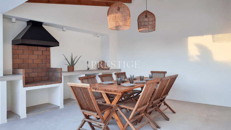 Dining area with a wooden table, wooden chairs, brick fireplace, and a kitchen area with a sink and faucet