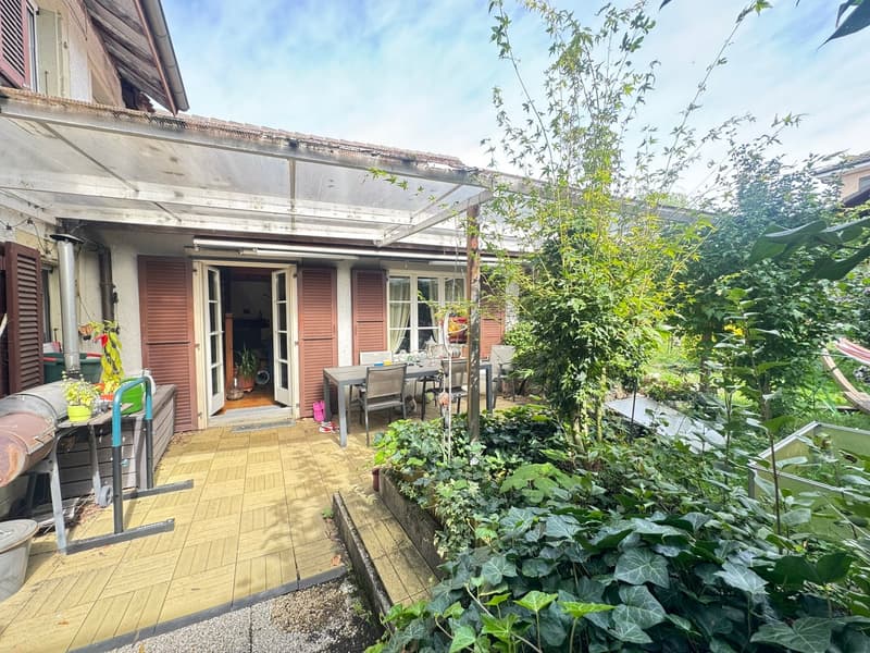 Patio with table and chairs, wooden pergola, plants and garden, paved floor