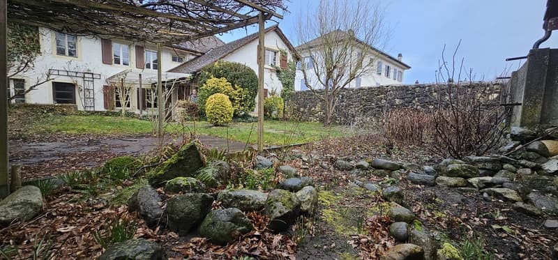 House: 2 stories, stone wall, garden, trees, shrubs, moss, rocks