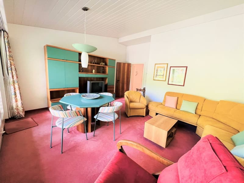 Colorful and retro-style living room with a dining table, chairs, a yellow sofa, and a built-in cabinet with shelves