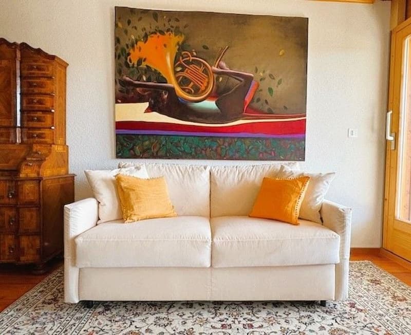 White sofa, white couch cushions, wooden cabinet, large painting, carpet, wooden door