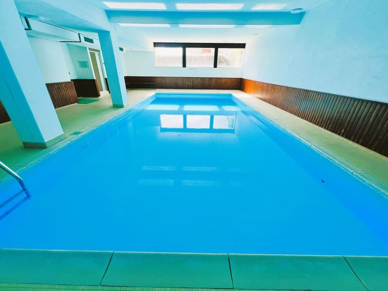 rectangular indoor swimming pool, blue water, white walls, wooden paneling