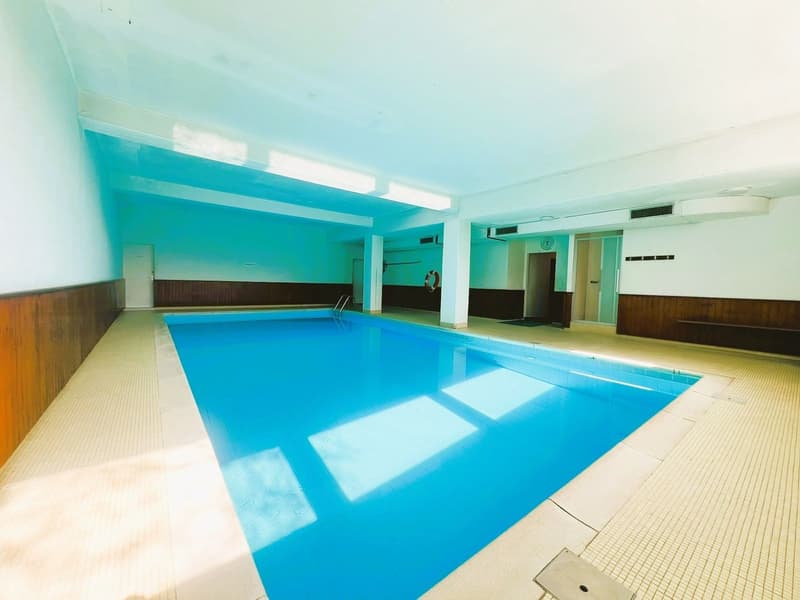 an indoor swimming pool with blue water, white walls, and tiled floor