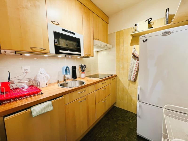 modern kitchen with wooden cabinets, tile flooring, white appliances, stainless steel sink, microwave, and dishwasher, gas stove with black oven, and a wooden countertop