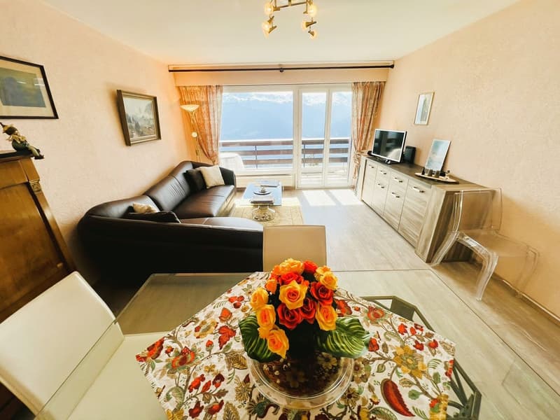 living room with couch, coffee table, TV, dining table with floral centerpiece, sideboard, lamp