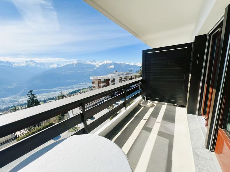 Outdoor balcony with railing, table, stunning mountain view
