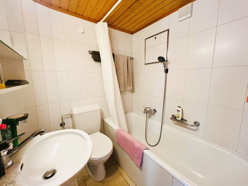 white tiles, white bathtub, white sink, white toilet, shower, towel rack, wooden ceiling