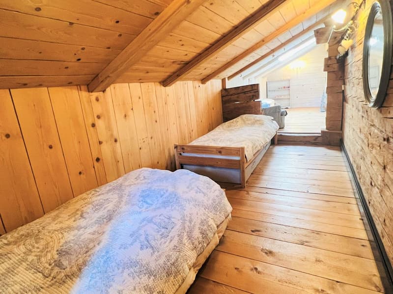 bedroom with wooden walls, wooden floor, two single beds, wooden headboard, small window