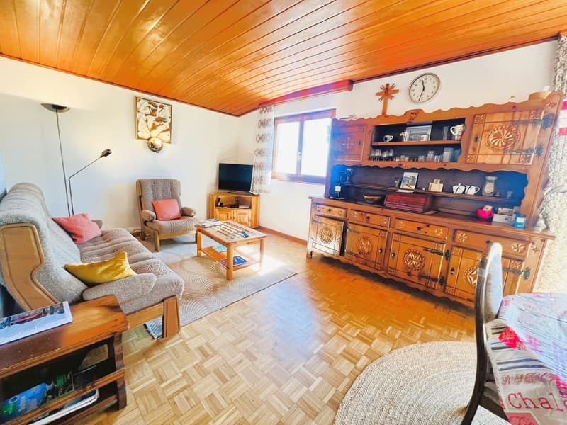 living room with sofa, coffee table, TV, wooden floor, wooden cabinet, window, clock, picture frame, lamp