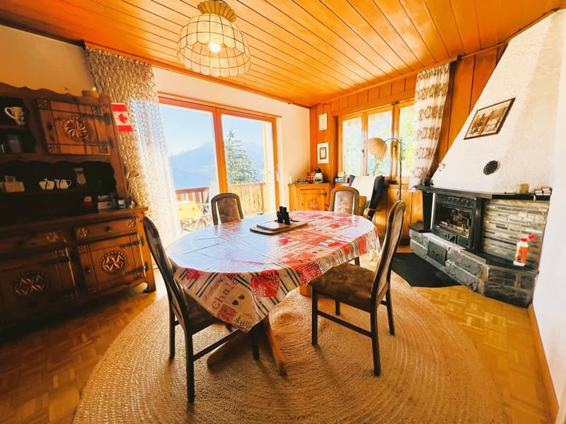 Dining room with wooden table, chairs, fireplace, wooden cabinet, and large windows with view