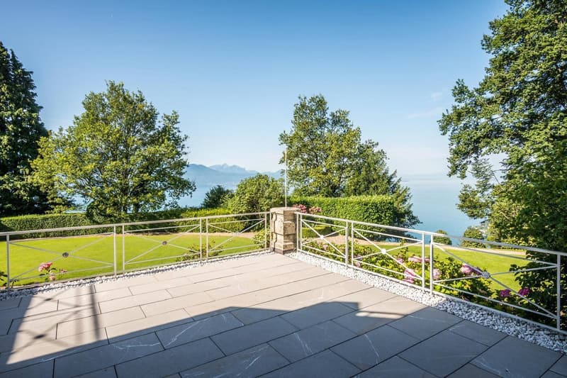large terrace with railings, overlooking a garden and ocean