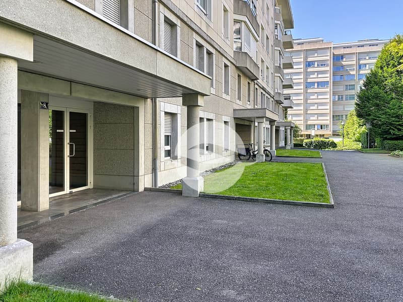 Entrée de l'immeuble avec parking visiteurs dans rue calme