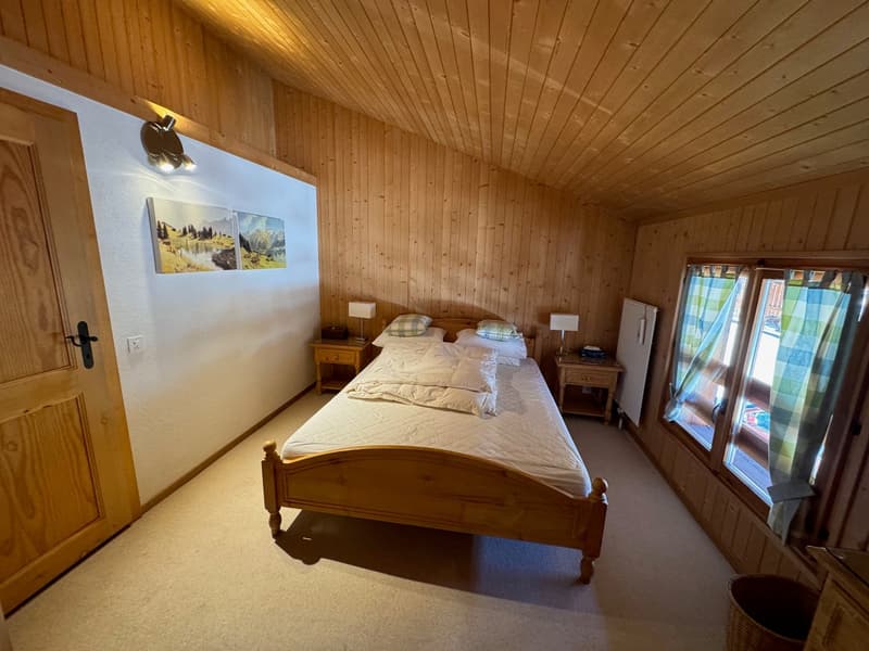 wooden walls, bed, two bedside tables with lamps, a door, two windows, radiator, waste basket
