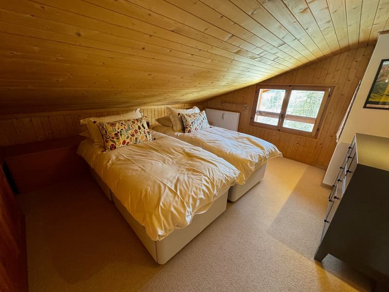 bedroom with 2 beds, wooden paneling, radiator, window, dresser