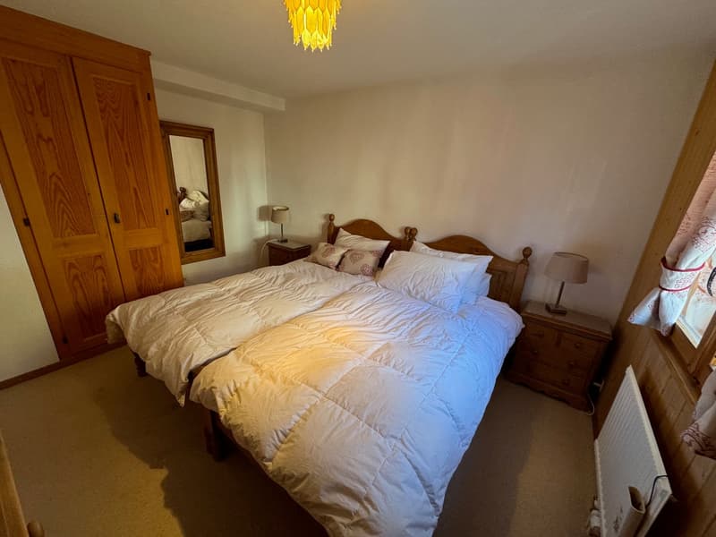 Double bed, hardwood floors, bedside tables with lamps, mirror, closet, and radiator.