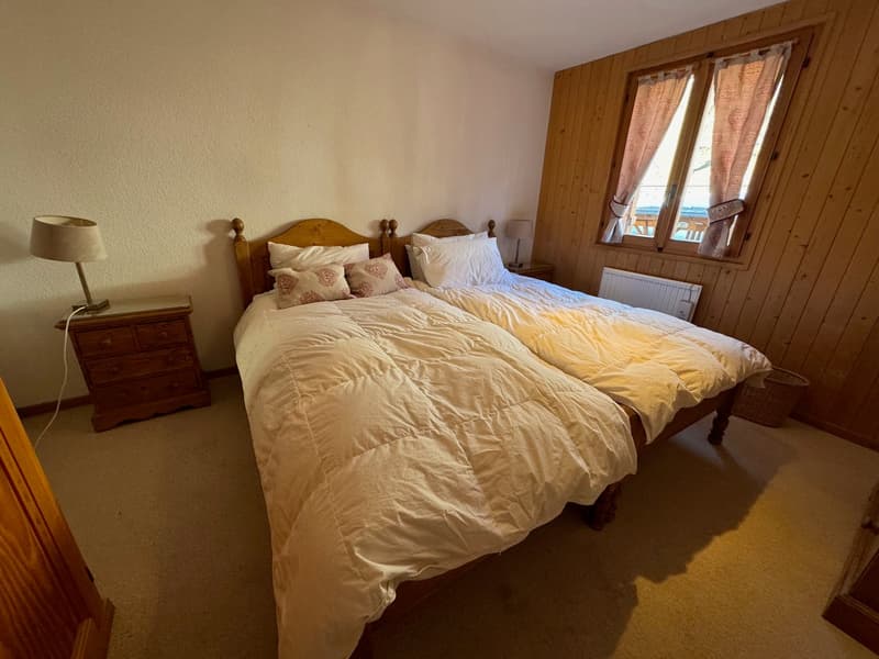 2 beds, wooden wall, lamp, nightstand, window with curtains