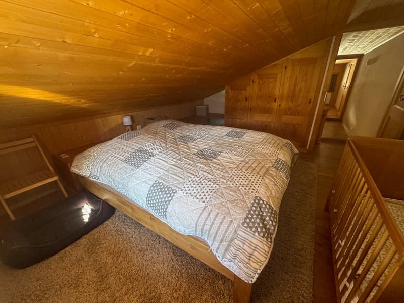 sloped ceiling, wooden bed, quilted blanket, carpeted floor, wardrobe, window, lamp, dog bed