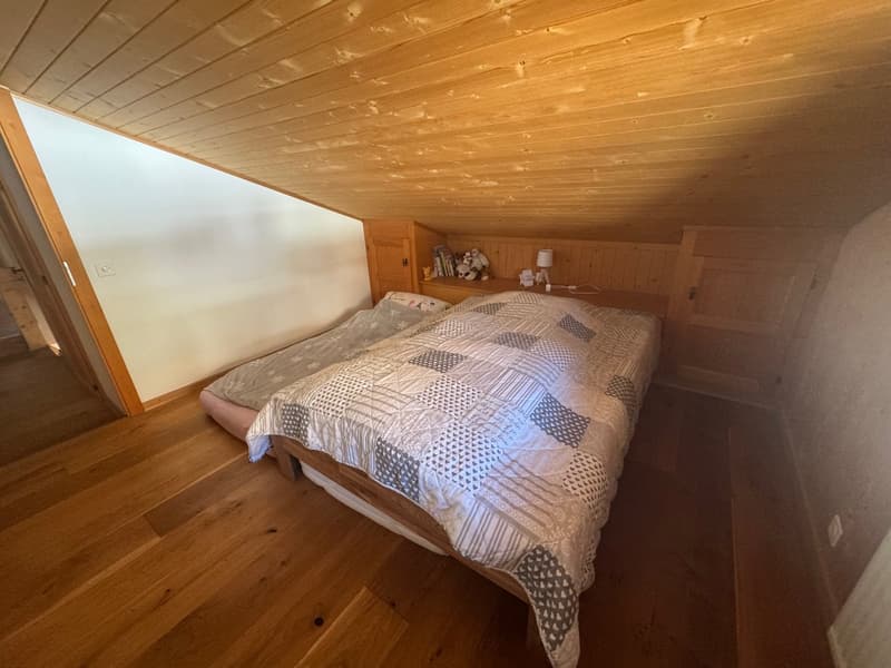 bedroom with wooden floor and wooden ceiling, two twin beds with quilts, and nightstands with lamps