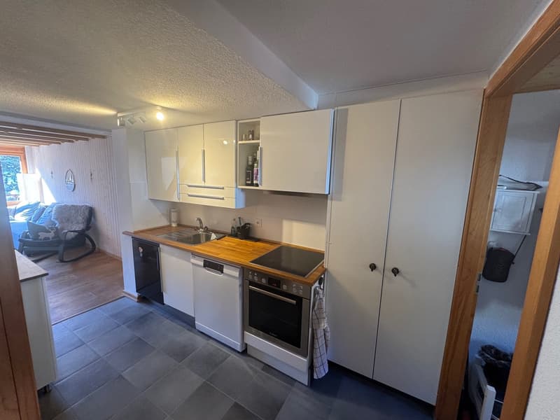 Modern kitchen, wooden counter top, white cabinets, dishwasher, stove, sink, tiled floor