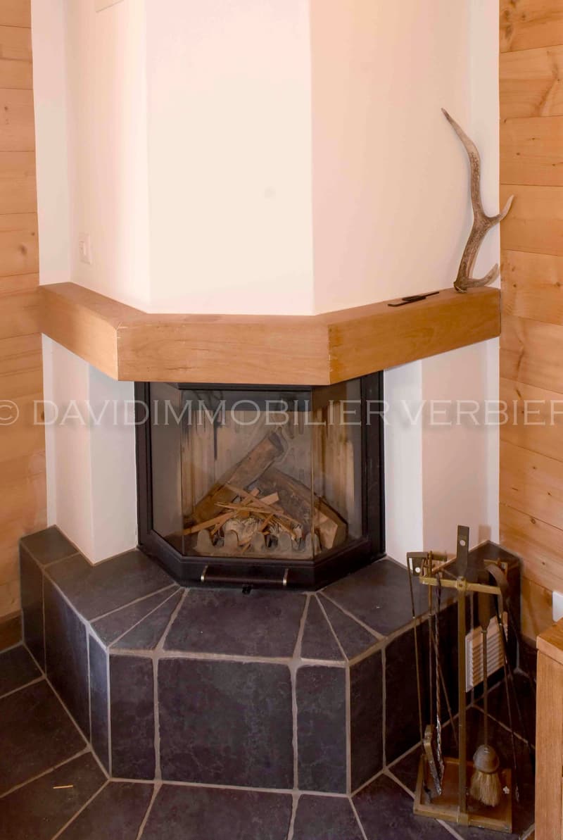 Corner fireplace, white wall, wooden paneling, fireplace tools